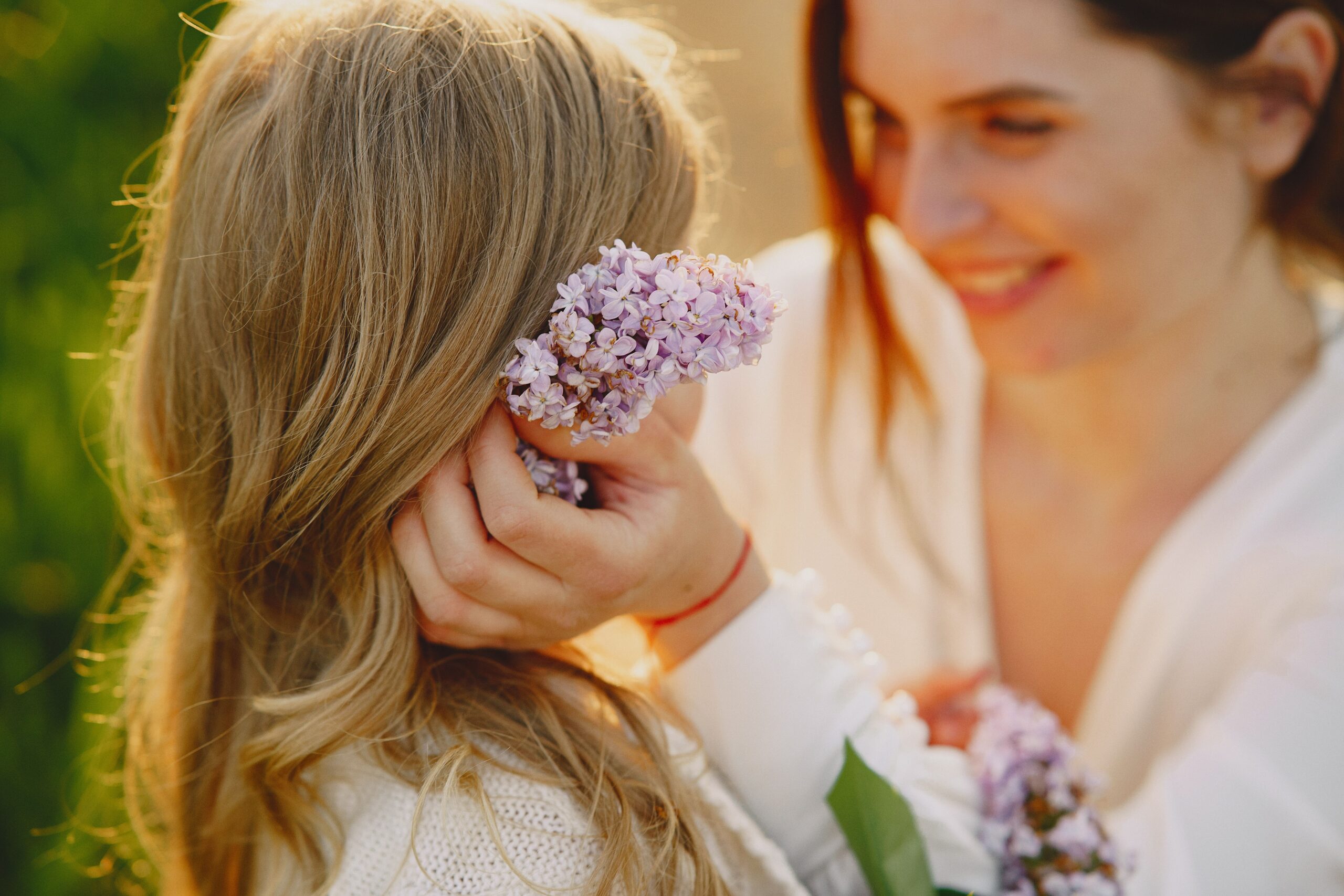 A joyful moment between mother and daughter enjoying lilac flowers during a spring day.
